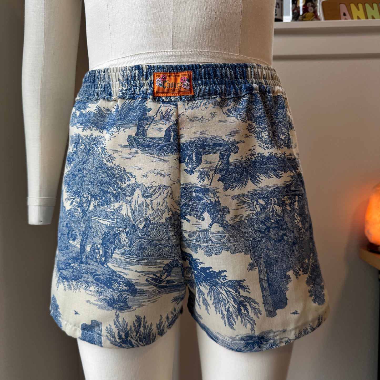 Blue and white patterned shorts on a mannequin with a blurred indoor background