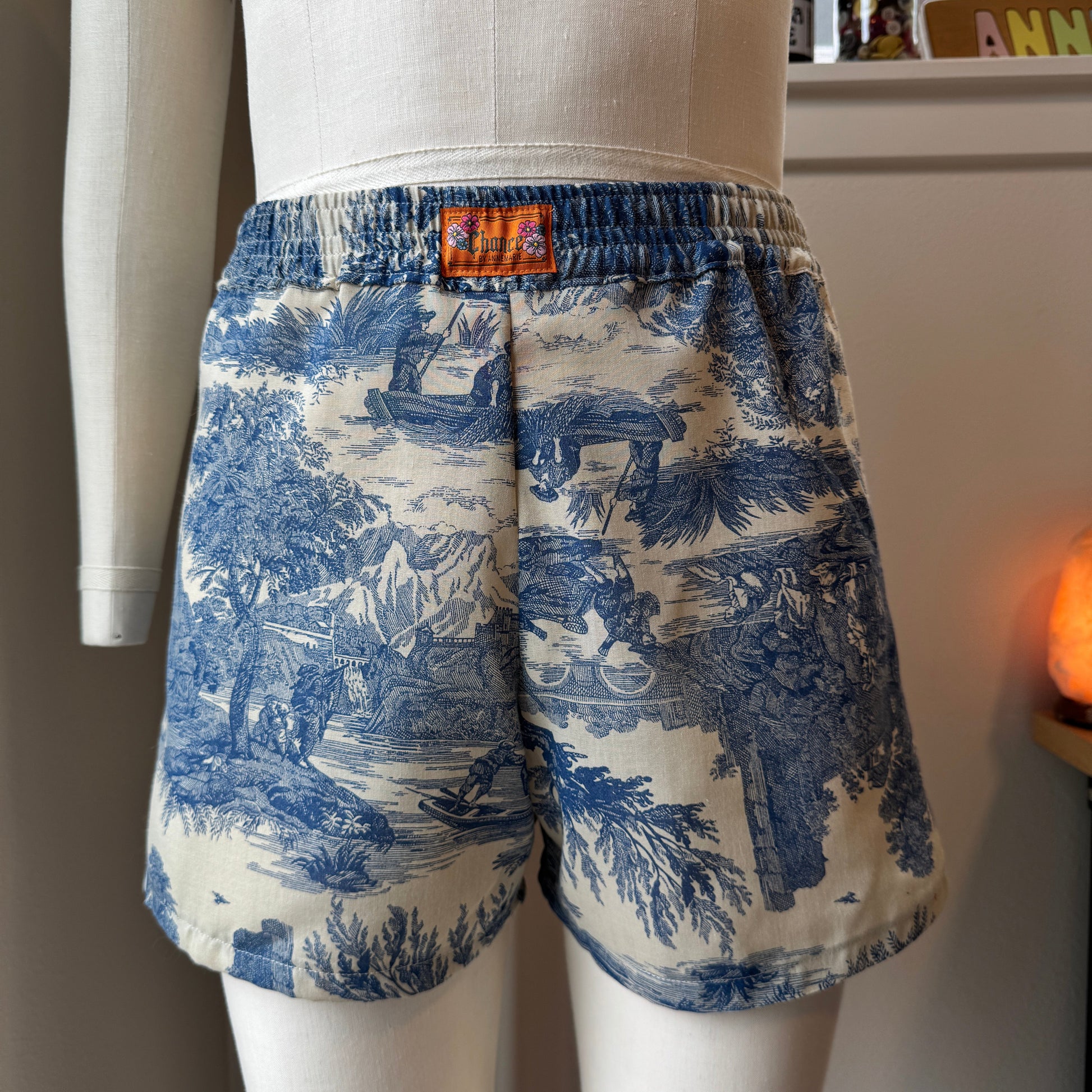 Blue and white patterned shorts on a mannequin with a blurred indoor background