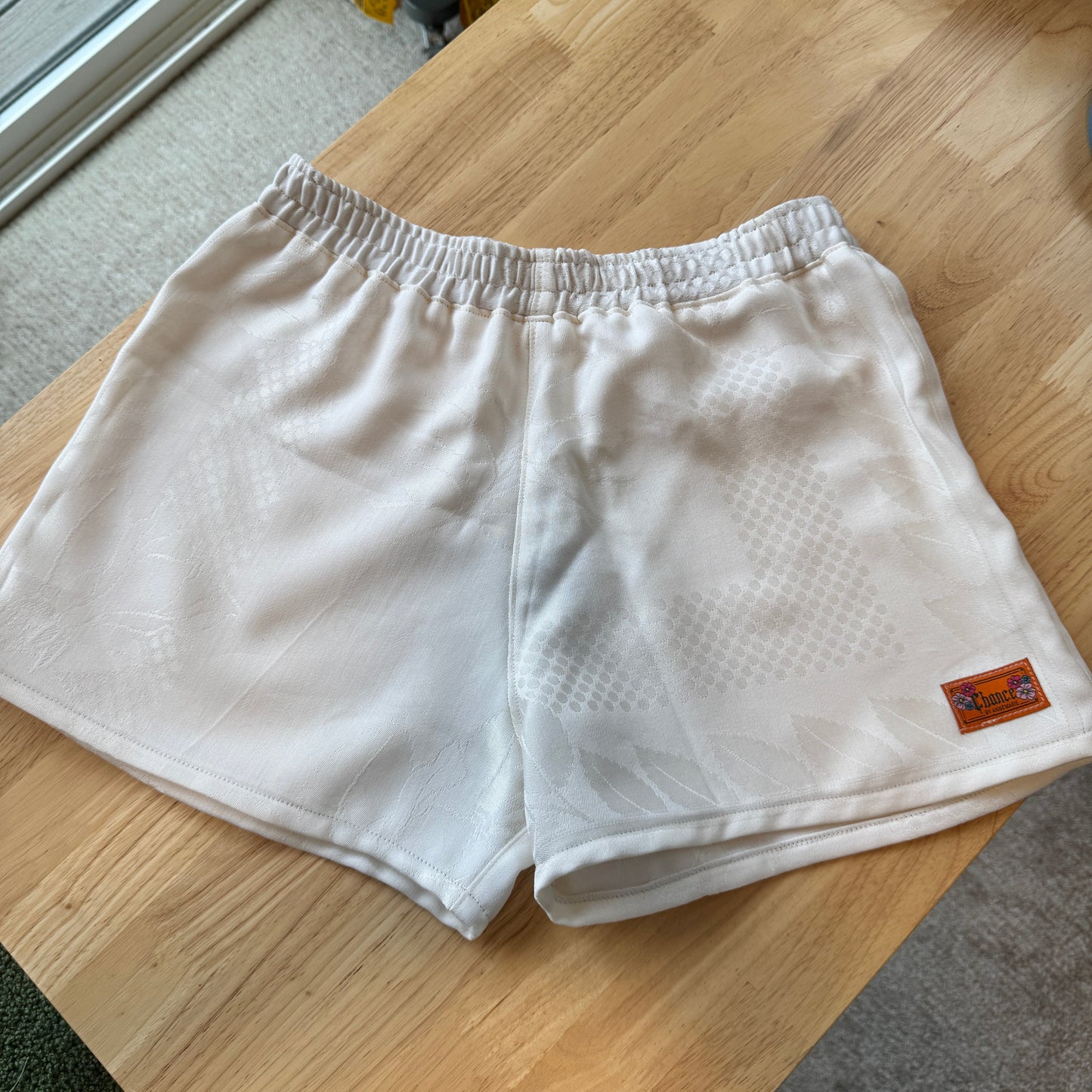 White shorts with a brand label on a wooden table